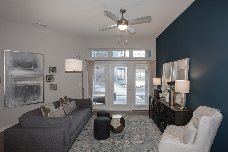 Large living room with a blue accent wall. Ceiling fan is displayed. Located at Midtown Apartments.