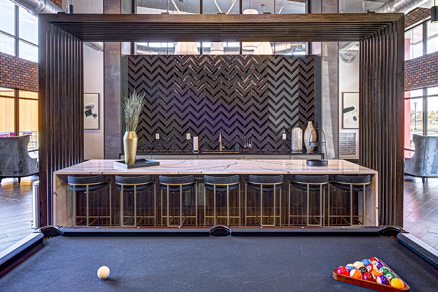 Pool table and bar seating inside the clubhouse of The State at Fishers apartments