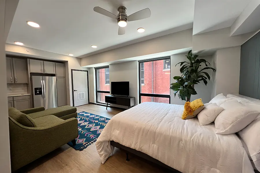 View of a bed, couch, and kitchen in a studio apartment